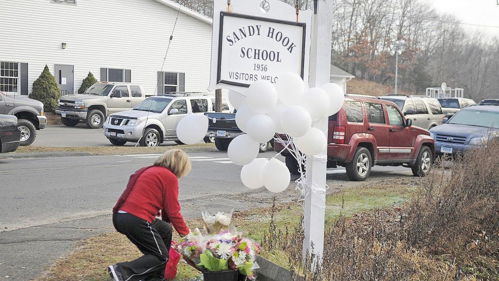 Trauer in Newtown: Eine Frau legt in Gedenken an die Opfer einen Kranz vor der Sandy Hook Elementary School ab. Foto: imago images/ZUMA Wire