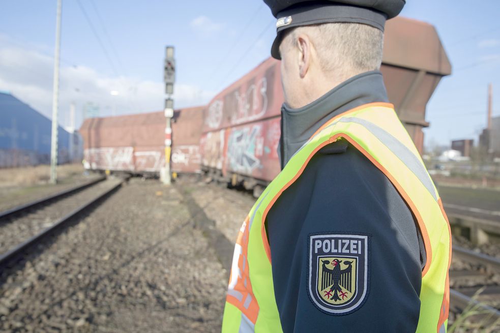 Ein Polizist am Ort des Unfalls in Bremen-Neustadt. Im Hintergrund: der entgleiste Güterzug. Bild: Jörg Sarbach/DPA