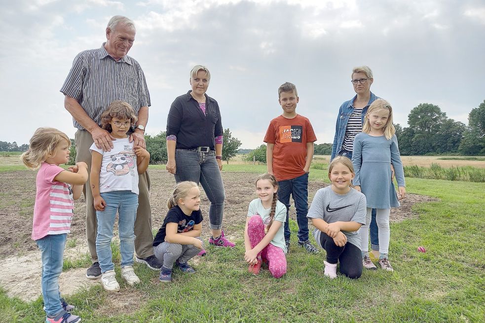 Außer dem dunklen Sand erinnert nicht mehr viel an den Spielplatz, auf dem Ida (von links), Enna, Timna, Temke, Fabian (hinten) Tomke und Finja oft spielten. Christian Sanders (von links), Tanja Oltrop und Ina Schullerer setzen sich dafür ein, dass die Geräte zurückkommen. Foto: Vogt