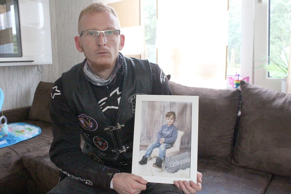 Lars Sass hält ein Foto seines kranken Sohnes Kilian (6) in der Hand. Am Sonnabend werden Motorrad-Fahrer am Haus der Familie vorbeifahren und Krach machen. Foto: Busemann