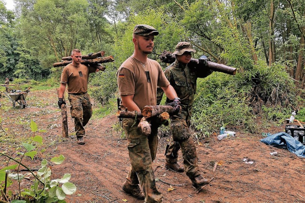 Die Soldaten der Bundeswehr müssen das Totholz teilweise per Hand wegschaffen, weil die Bagger auf dem durchweichten Gelände nicht fahren können. Foto: Polat