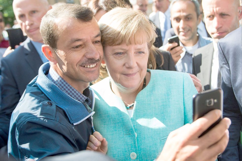 Bundeskanzlerin Angela Merkel (CDU) lässt sich am 10.09.2015 nach dem Besuch einer Erstaufnahmeeinrichtung für Asylbewerber in Berlin-Spandau für ein Selfie zusammen mit einem Flüchtling fotografieren. Foto: Bernd von Jutrczenka/dpa