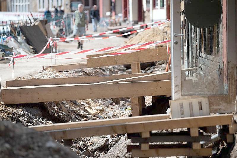 Mit Holzbrücken gelangen Anwohner in der zerstörten Altstadt von Bad Münstereifel in ihre Häuser. Die Flutkatastrophe Mitte Juli hat bislang Versicherungsschäden von rund sieben Milliarden Euro verursacht und damit mehr als bisher erwartet. Foto: Federico Gambarini/dpa