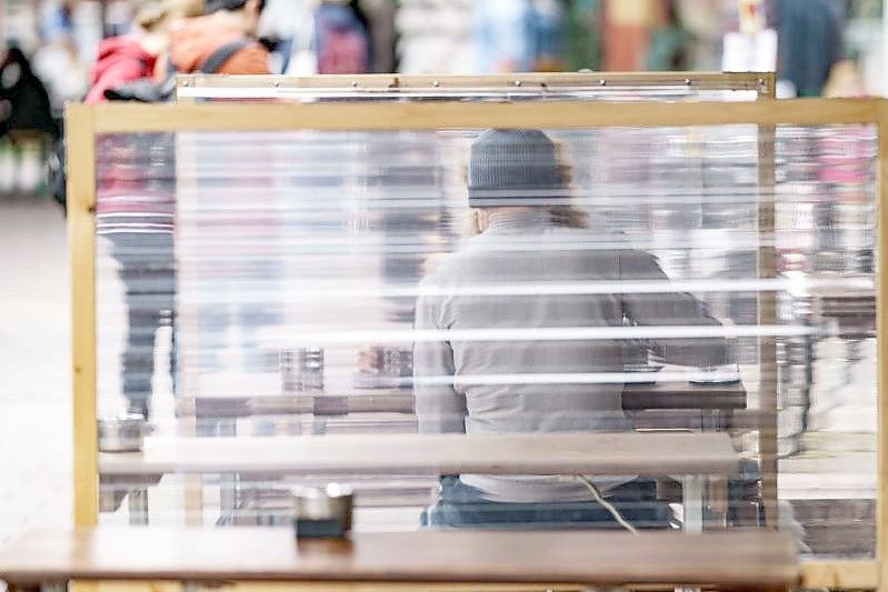 Gäste eines Restaurants warten zwischen Plexiglas-Trennscheiben auf ihre Bestellung. In Hamburg gilt ab dem Wochenende die sogenannte 2G Regelung. Foto: Axel Heimken/dpa