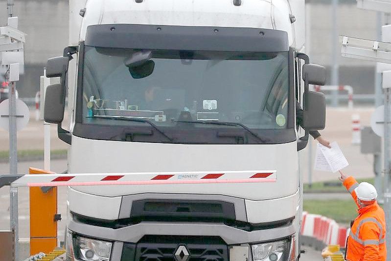 Die Dokumente eines Lastwagenfahrers werden kontrolliert, als der Lkw den Check-in für den Zug durch den Eurotunnel passiert. Foto: Frank Augstein/AP/dpa