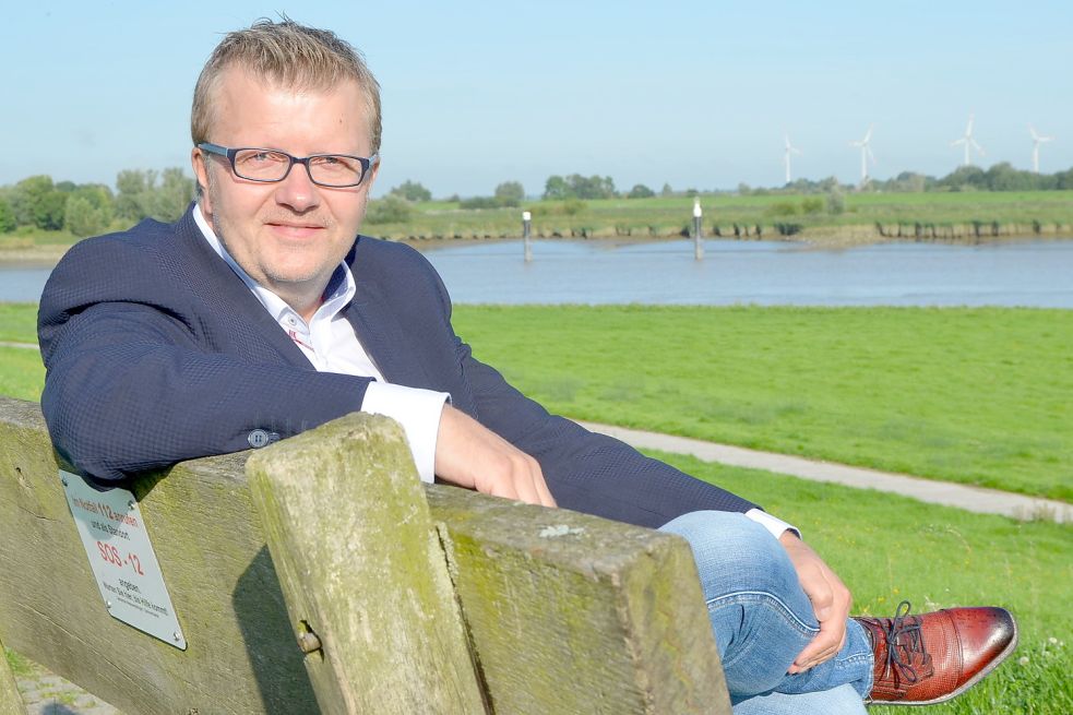 Westoverledingens Bürgermeister Theo Douwes sitzt auf dem Deich beim Schöpfwerk des Muhder Sieltiefs im Ortsteil Esklum, um von dort auf den Zusammenfluss von Leda und Ems zu blicken. Es ist ein strategisch wichtiger und geschichtsträchtiger Ort im Gemeindegebiet, den Douwes gern als Rastplatz für seine Radtouren nutzt. Foto: Fertig