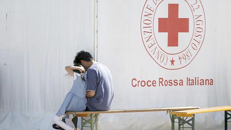 Ein Mann und ein Kind sitzen in einem Einsatzzentrum des italienischen Roten Kreuzes, Croce Rossa Italiana (CRI). Dort werden mit Hilfe der Armee und des Zivilschutzes afghanische Geflüchtete aufgenommen. Foto: Cecilia Fabiano/LaPresse via ZUMA Press/dpa
