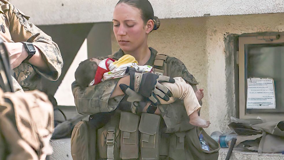 In diesem Bild vom 20. August 2021, das vom US Marine Corps zur Verfügung gestellt wurde, beruhigte Nicole Gee ein Kleinkind während einer Evakuierung am Hamid Karzai International Airport in Kabul, Afghanistan. Tage später starb die 23-Jährige bei einem Terroranschlag auf den Flughafen. Foto: Sgt. Isaiah Campbell / U.S. Marine Corps via AP/dpa