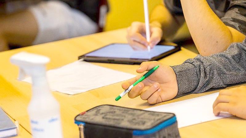 Ein Schüler hält beim Unterricht in seiner Klasse einen Stift, während ein anderer mit einem Tablet arbeitet. Foto: Philipp von Ditfurth/dpa