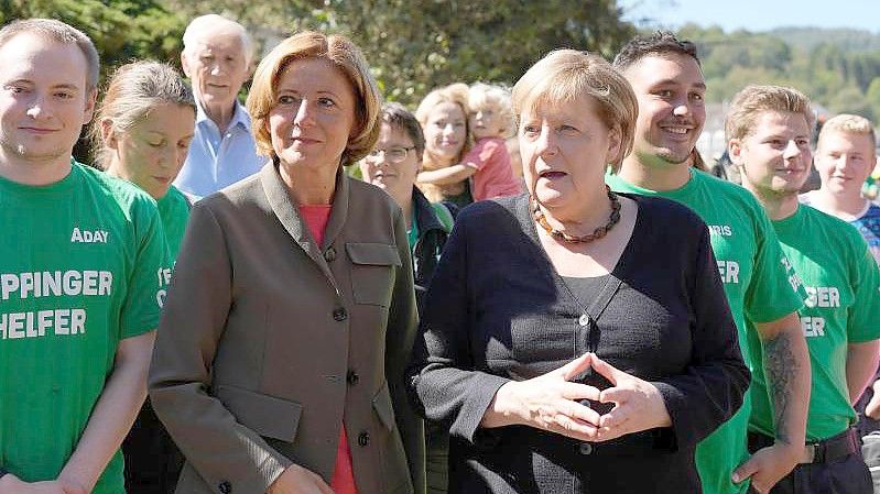 Bundeskanzlerin Angela Merkel (CDU, r.) steht mit freiwilligen Helfern neben der rheinland-pfälzischen Ministerpräsidentin Malu Dreyer bei ihrem Besuch im hochwassergeschädigten Altenahr. Foto: Markus Schreiber/AP-Pool/dpa