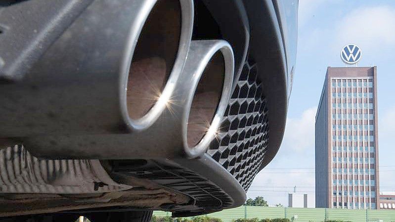 Auspuffrohre eines Volkswagen, fotografiert mit dem Markenhochhaus am VW Werk Wolfsburg. (Archivbild). Foto: Julian Stratenschulte/dpa