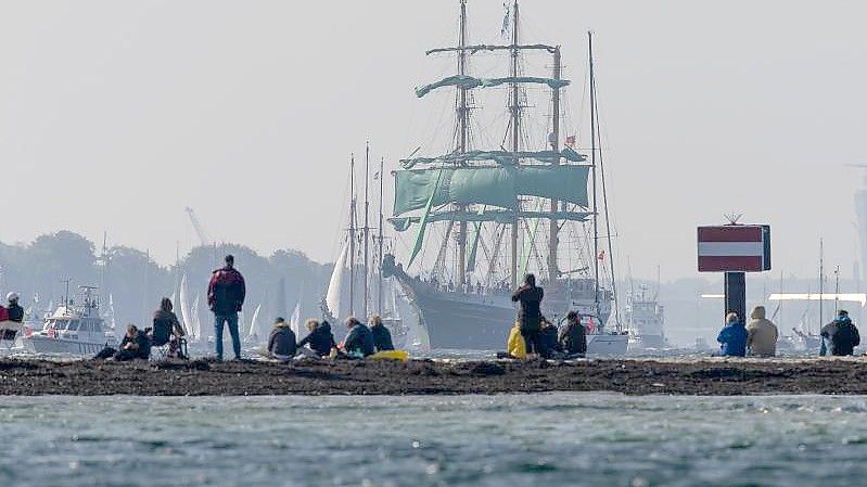 Zuschauer beobachten am Falkensteiner Strand die Windjammerparade der Kieler Woche. Foto: Frank Molter/dpa