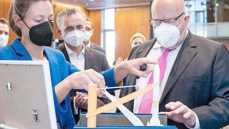 Peter Altmaier (r, CDU), Bundesminister für Wirtschaft und Energie, sieht sich das Modell einer möglichen Raketen-Startplattform der GOSA in der Nordsee an. Foto: Bernd von Jutrczenka/dpa