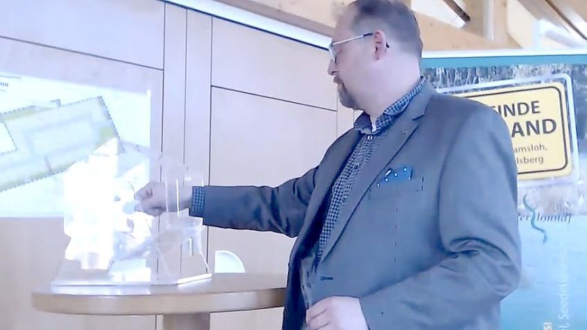 Saterlands Bürgermeister Thomas Otto im April 2021 bei der Ziehung der Lose für das Neubaugebiet in Ramsloh-Witteberg. So ähnlich wird es auch am Donnerstag, 9. September, im Saterländer Rathaus wieder laufen. Dann werden die Grundstücke für das Strücklinger Baugebiet Loange Fäilde vergeben. Screenshot: Fertig