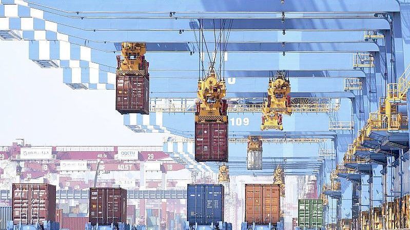 Portalkräne bewegen Container auf Transporter in einem Hafen in Qingdao in der ostchinesischen Provinz Shandong. Foto: Uncredited/CHINATOPIX/dpa