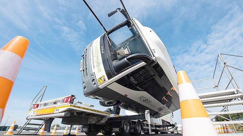 Bei dem Versuchsaufbau auf dem Crashtestgelände kippt ein kleiner mit Insassen besetzter Reisebus per Hydraulik um 90 Grad auf die Seite. Foto: Guido Kirchner/dpa