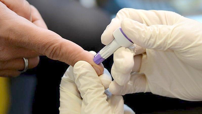 Ein Arzt nimmt an dem Finger eines jungen Mannes Blut ab. In vielen Ländern ist die Zahl der HIV-Tests in der Pandemie zurückgegangen. Foto: Britta Pedersen/dpa-Zentralbild/dpa