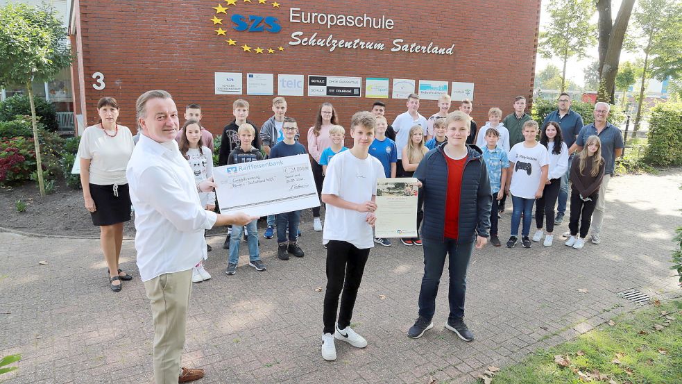 Die Schülerinnen und Schüler der Haupt- und Realschule Saterland überreichten den symbolischen Scheck vor ihrer Schule in Ramsloh an Joachim Graf von Arnim. (links) Er ist ehrenamtlicher Mitarbeiter des Bündnisses „Aktion Deutschland Hilft“. Foto: Passmann