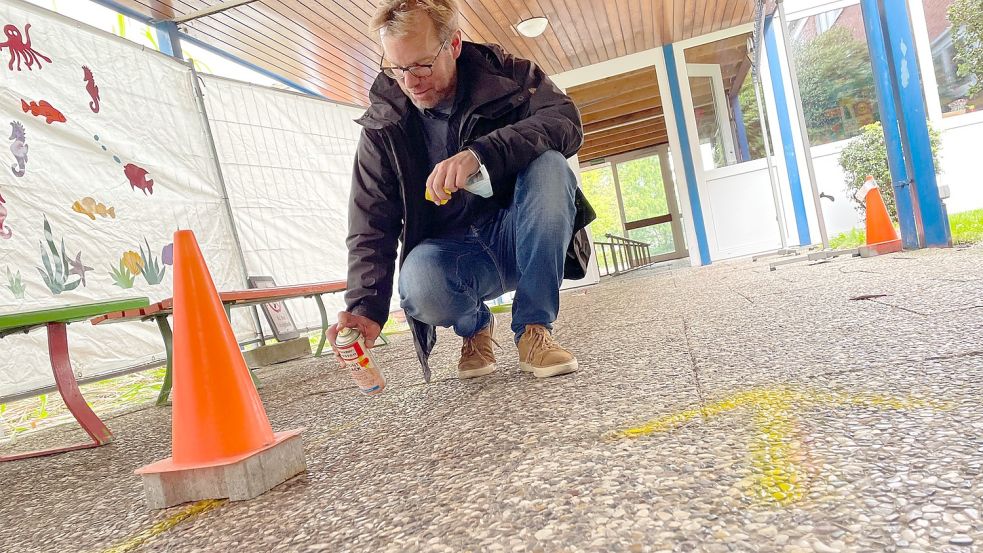 Schulleiter Timo Dogs sprayte an diesem Freitag im Sinne der Corona-Schutzmaßnahmen mit gelber Farbe die vorgegebene Laufrichtung auf die Gänge. Foto: Janßen