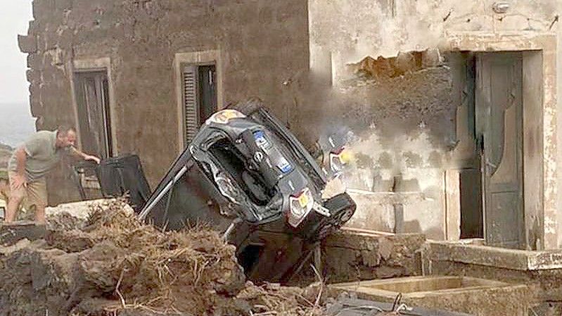 Ein zerstörtes Fahrzeug liegt abseits der Straße an einem Haus. Auf der italienischen Mittelmeerinsel Pantelleria sind zwei Menschen bei einem Unwetter ums Leben gekommen. Foto: Vigili del Fuoco/dpa