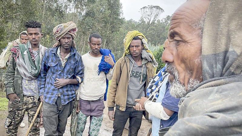 Männer versammeln sich, um mit dem am Arm verletzten Milizionär Kibret Bidere (2.v.r) in der Nähe des Dorfes in der Amhara-Region in Nordäthiopien zu sprechen. Foto: Uncredited/AP/dpa