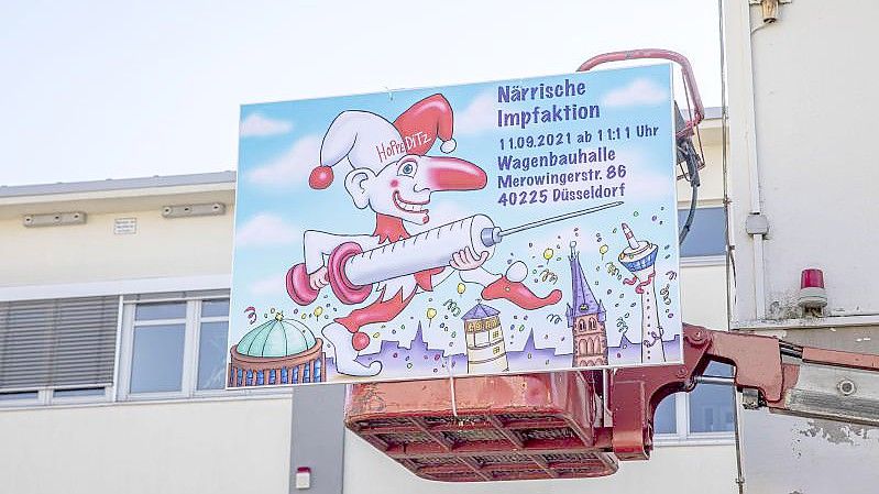 "Närrische Impfaktion" steht auf einem Schild an der Wagenbauhalle in Düsseldorf. Foto: Malte Krudewig/dpa