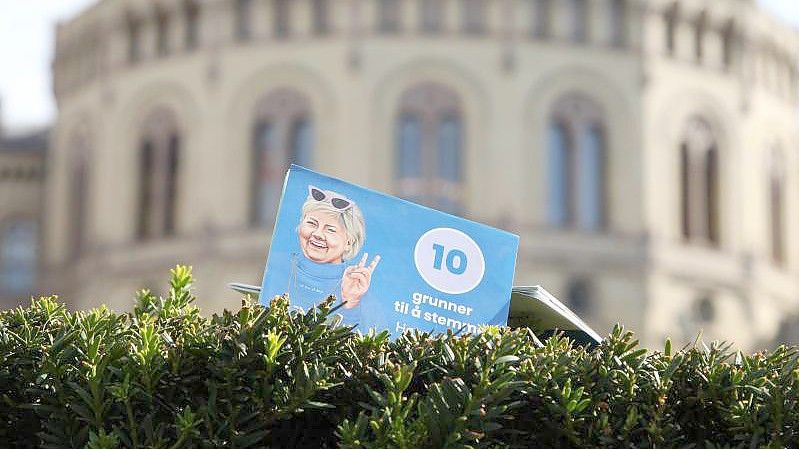 Ein Flyer der norwegischen Regiergungschefin Erna Solberg steckt vor dem Parlament in Oslo in einer Hecke. Bewahrheiten sich die Umfragen, dann ist die Regierungszeit der konservativen Ministerpräsidentin nach acht Jahren zu Ende. Foto: Steffen Trumpf/dpa