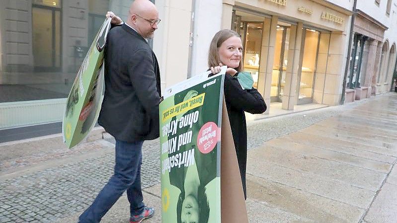 Wolfgang Wetzel, (l) Spitzenkandidat der Grünen und Christin Furtenbacher, Landesvorstandssprecherin der Grünen in Sachsen, laufen mit Wahlplakaten durch die Innenstadt von Zwickau. Foto: Bodo Schackow/dpa-Zentralbild/dpa