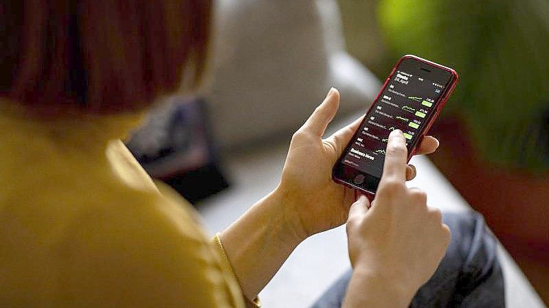 Eine Frau beobachtet mit ihrem iPhone die Aktienkurse in der App Stocks. Foto: Fabian Sommer/dpa