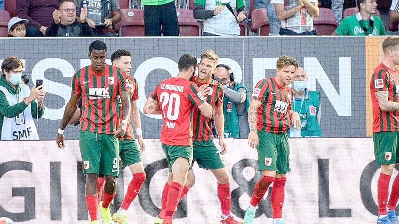 Augsburgs Torschütze Florian Niederlechner (M) jubelt mit seiner Mannschaft über den Treffer zum 1:0. Foto: Matthias Balk/dpa