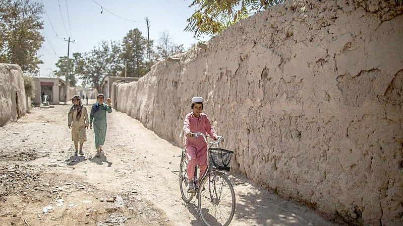 Ein afghanischer Junge fährt in Isa Khel außerhalb von Kundus Fahrrad. Foto: Oliver Weiken/dpa