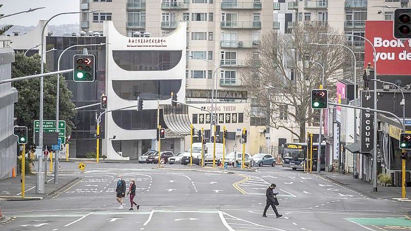Menschen überqueren im zentralen Geschäftsviertel in Auckland fast leere Straßen. Foto: Michael Craig/New Zealand Herald/dpa