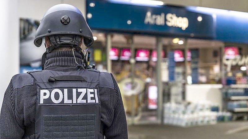 Ein Polizist steht vor der Tankstelle, an der ein Angestellter von einem Mann erschossen worden ist. Foto: Christian Schulz/Foto Hosser/dpa