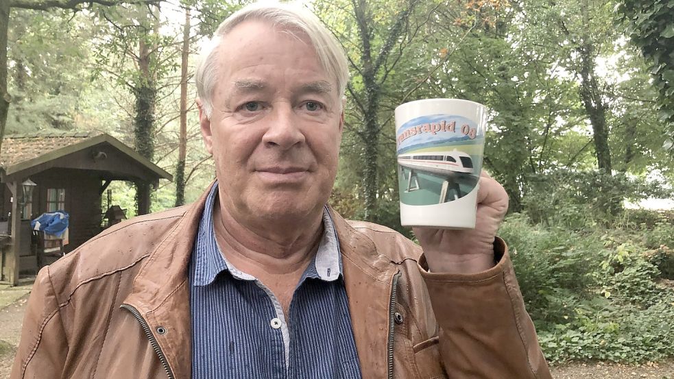 Wilfried Stubbe hält eine Tasse hoch, die der Touristikverein Dörpen herausgegeben hat und auf der der Transrapid 08 zu sehen ist. Fotos: Zein
