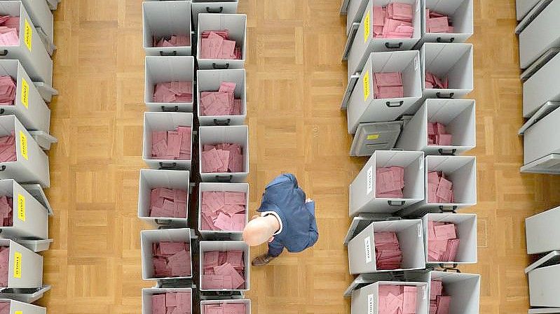 Markus Blocher, Kreiswahlleiter, begutachtet in einer Wahlbehörde zahlreiche Wahlurnen gefüllt mit Stimmzettelumschlägen für die Briefwahl. Foto: Sebastian Kahnert/dpa-Zentralbild/dpa