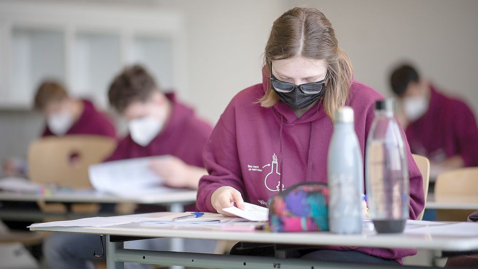 Eine Schülerin mit medizinischer Maske liest sich am ersten Tag der Abiturprüfungen die Abituraufgaben durch. Foto: Symbolfoto: Sebastian Gollnow/dpa