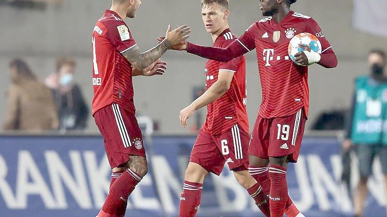 Alphonso Davies (r) klatscht nach dem Sieg mit Lucas Hernández (l) ab. Daneben steht Joshua Kimmich. Foto: Daniel Karmann/dpa