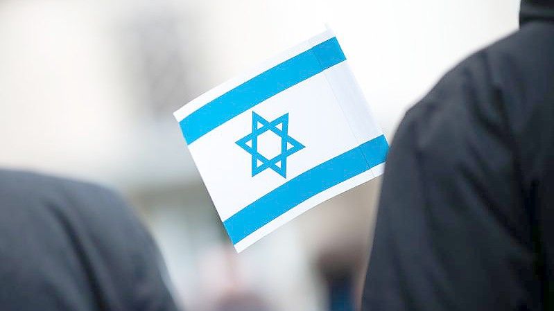 Bei einer Solidaritätskundgebung vor einer Synagoge hält ein Teilnehmer eine israelische Flagge in der Hand. Foto: Jonas Güttler/dpa