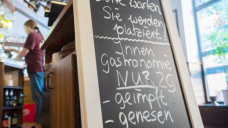 Eine Tafel mit der Aufschrift „Innengastronomie - Nur 2G - geimpft - genesen“ steht in Schadt’s Brauerei Gasthaus. Foto: Julian Stratenschulte/dpa