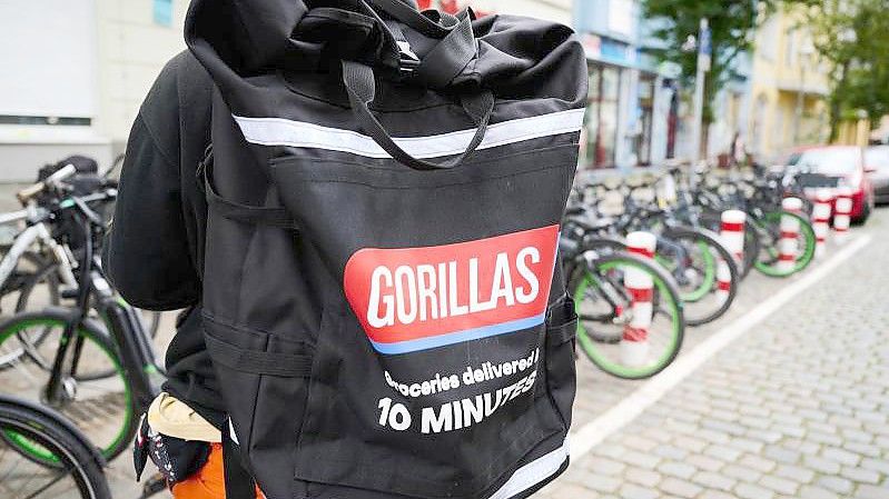Ein Beschäftigter des Lieferdienstes Gorillas trägt einen Rucksack und steht vor den Fahrrädern. Foto: Annette Riedl/dpa/Archiv
