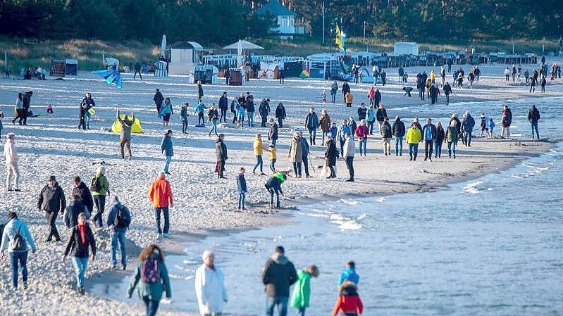 Touristen am Strand vor der Seebrücke im Ostseebad Binz. Foto: Stefan Sauer/dpa