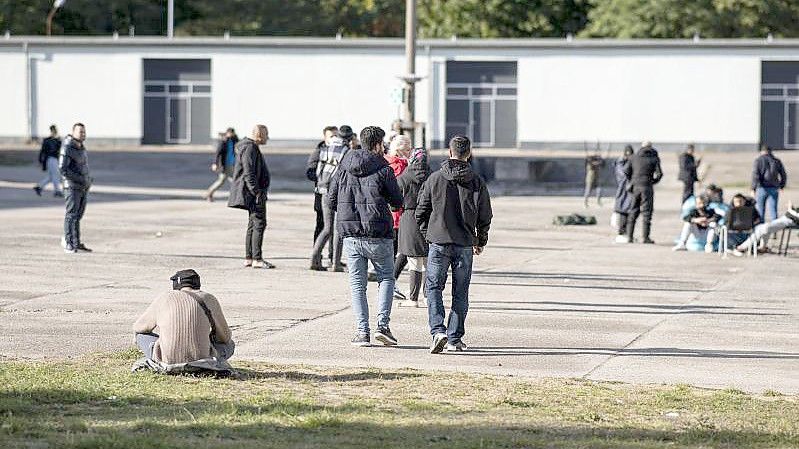 Asylsuchende laufen in der Erstaufnahmeeinrichtung Eisenhüttenstadt über einen Platz. (Archivbild). Foto: Fabian Sommer/dpa