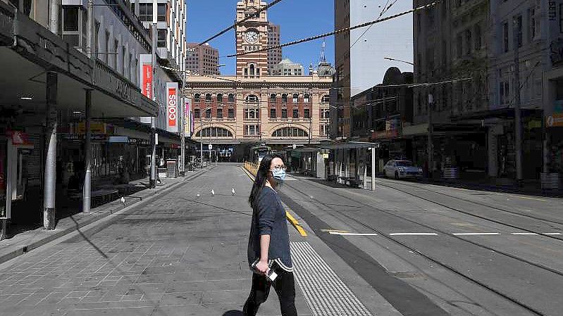 Eine Person mit Gesichtsmaske geht über die Straße in Melbourne. Foto: James Ross/AAP/dpa