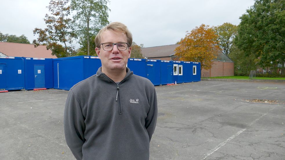 Timo Dogs, Leiter der Grundschule, steht vor Containern. Dort sind derzeit die Verwaltung und das Lehrerzimmer sowie die Sanitäranlagen für die Schüler und Schülerinnen untergebracht.