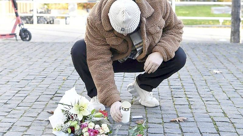 Ein Mann legt am Tatort Blumen und eine Kerze für den Musiker Einár nieder. Foto: Henrik Montgomery/TT NEWS AGENCY/dpa