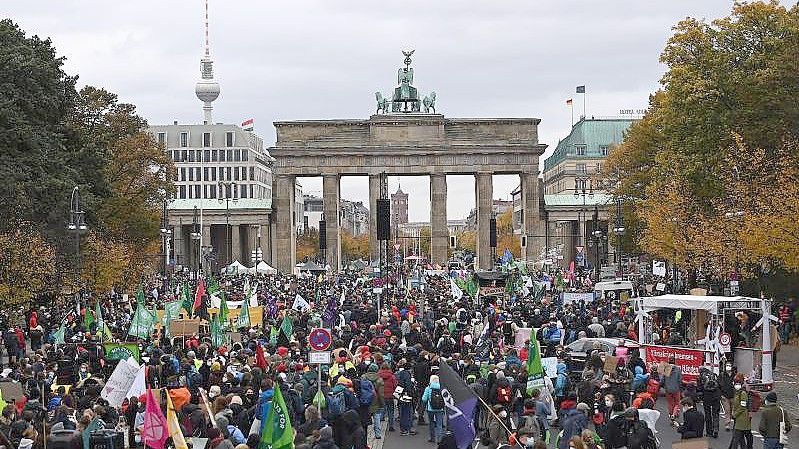 „We need Action“: Ein Teilnehmer mit einem Transparent vor dem Brandenburger Tor. Foto: Philipp Znidar/dpa