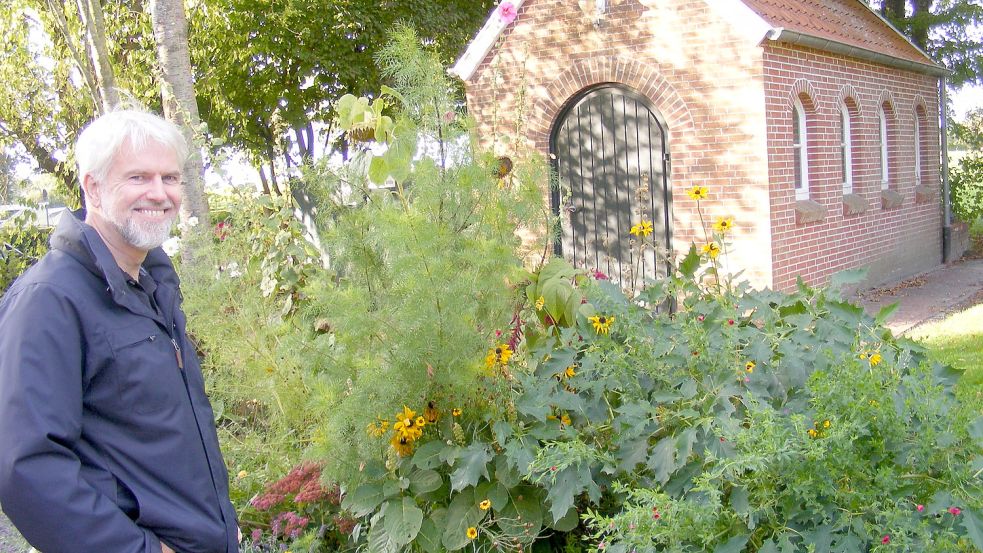 Den Friedhof in Kirchborgum möchte Friedrich Bruns weitgehend ökologisch gestalten und damit den Anstoß für weitere Projekte dieser Art geben. Das Foto zeigt ihn vor einem Blühstreifen bei der Leichenhalle, den seine Frau Bettina angelegt hat. Foto: Szyska
