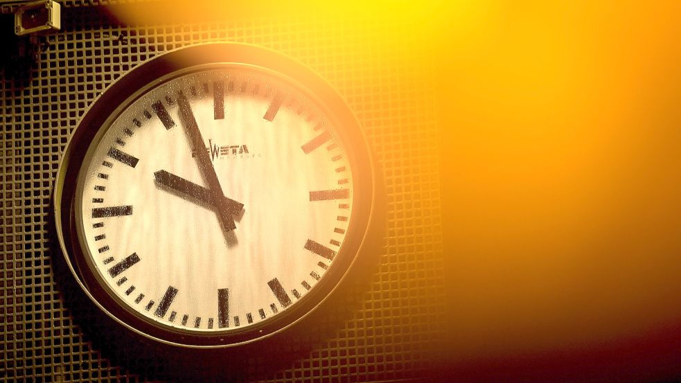 Gelbes Licht scheint auf eine Uhr im nächtlichen Dunkel: In der Nacht zum Sonntag wird die Zeit um eine Stunde zurück gestellt - dann gilt wieder Winterzeit. Foto: Schuldt/DPA