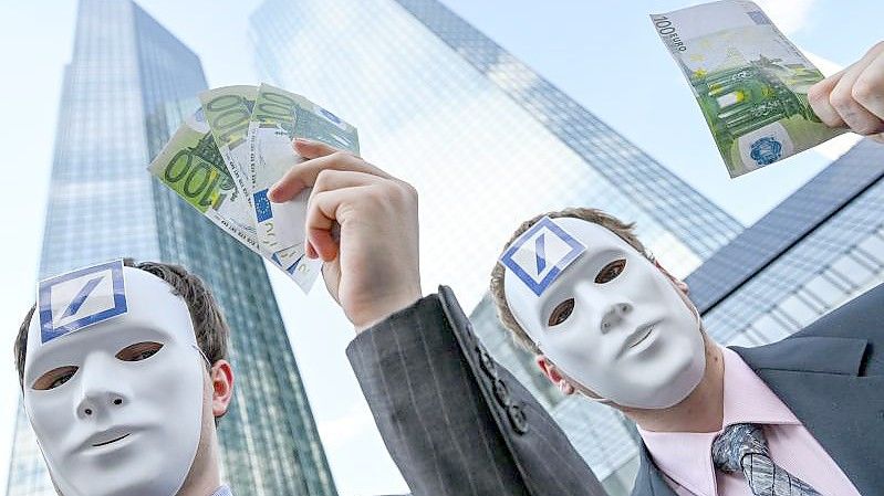 Mitglieder von Attac, die weiße Masken mit dem Logo der Deutschen Bank tragen, stehen beim zentralen Klimastreik von Fridays for Future vor der Zentrale der Deutschen Bank. Foto: Arne Dedert/dpa