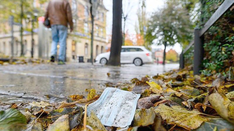 Ein Mundschutz zwischen herbstlich gefärbten Blättern in der Altstadt von Pirna. Foto: Robert Michael/dpa-Zentralbild/dpa